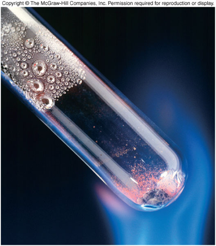 A picture of a glass tube containing mercury(II) oxide being heated and it is being converted into liquid mercury.